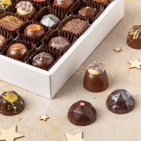 a top down view of a festive collection chocolate box by chococo with star anise, cloves and cardamon scattered about 