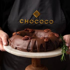 vegan dark chocolate wreath being held on a marble top cake stand handcrafted by Chococo 
