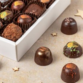 a small box of 9 handcrafted vegan dark handcrafted festive chocolates by Chococo with yellow gold star lid with wooden stars scattered around 