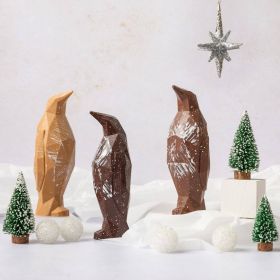Dark chocolate geometric penguin by Chococo looking up to a north star silver Christmas decoration in a snowy forest with Christmas trees around 