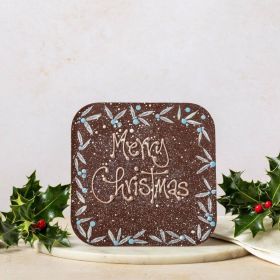 giant dark chocolate bar with hand pipped Merry Christmas message. hand decorated with holly design and surrounded by holly, on a marble plate and linen napkin 